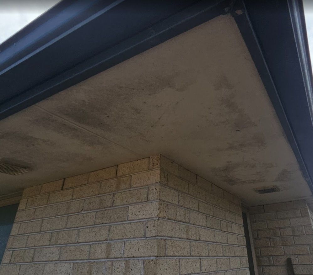 Roof-to-wall junction viewed from ground level showing staining and loose flashing
