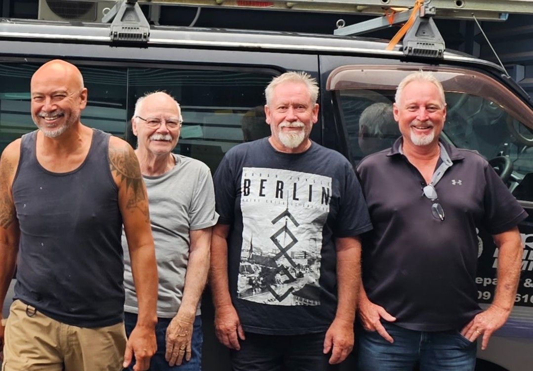 Four men standing in front of a work van