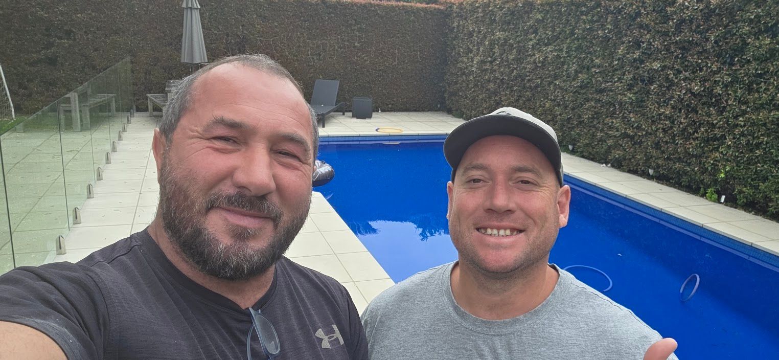 Two men taking a selfie beside a swimming pool