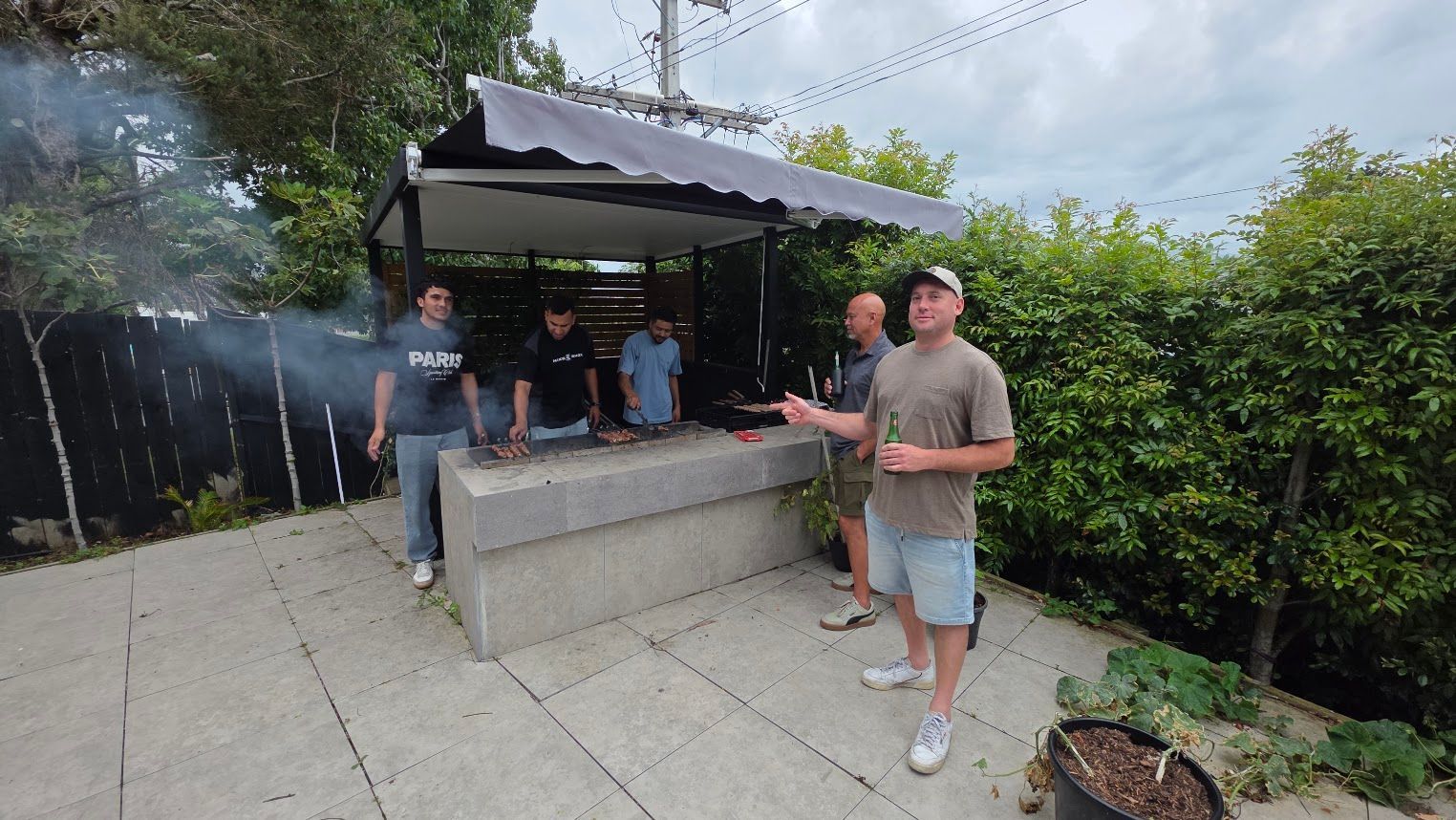 People gathered around an outdoor barbecue shelter