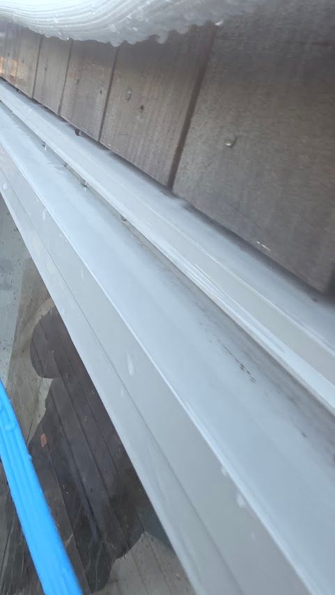 Close-up of aluminium door head flashing showing water path climbing the gap between drip edge and j