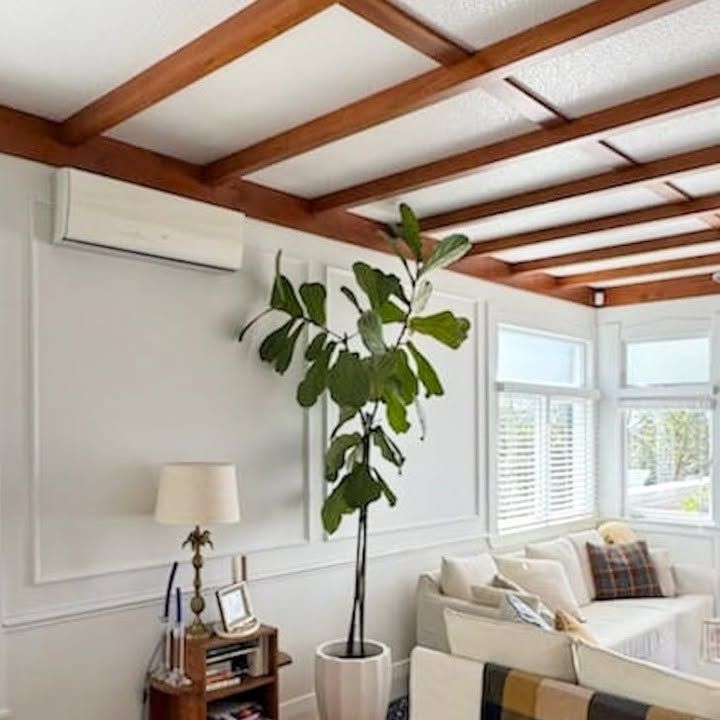 Room with dark wood beam ceiling and wall-mounted air conditioning unit