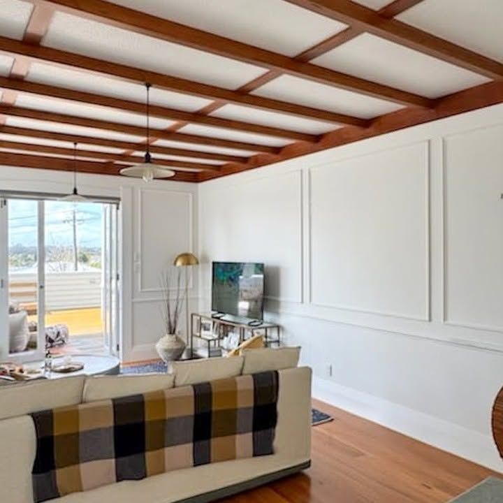 Room with wood beam Living room with black-framed bifold doors opening to a poolceiling and window view