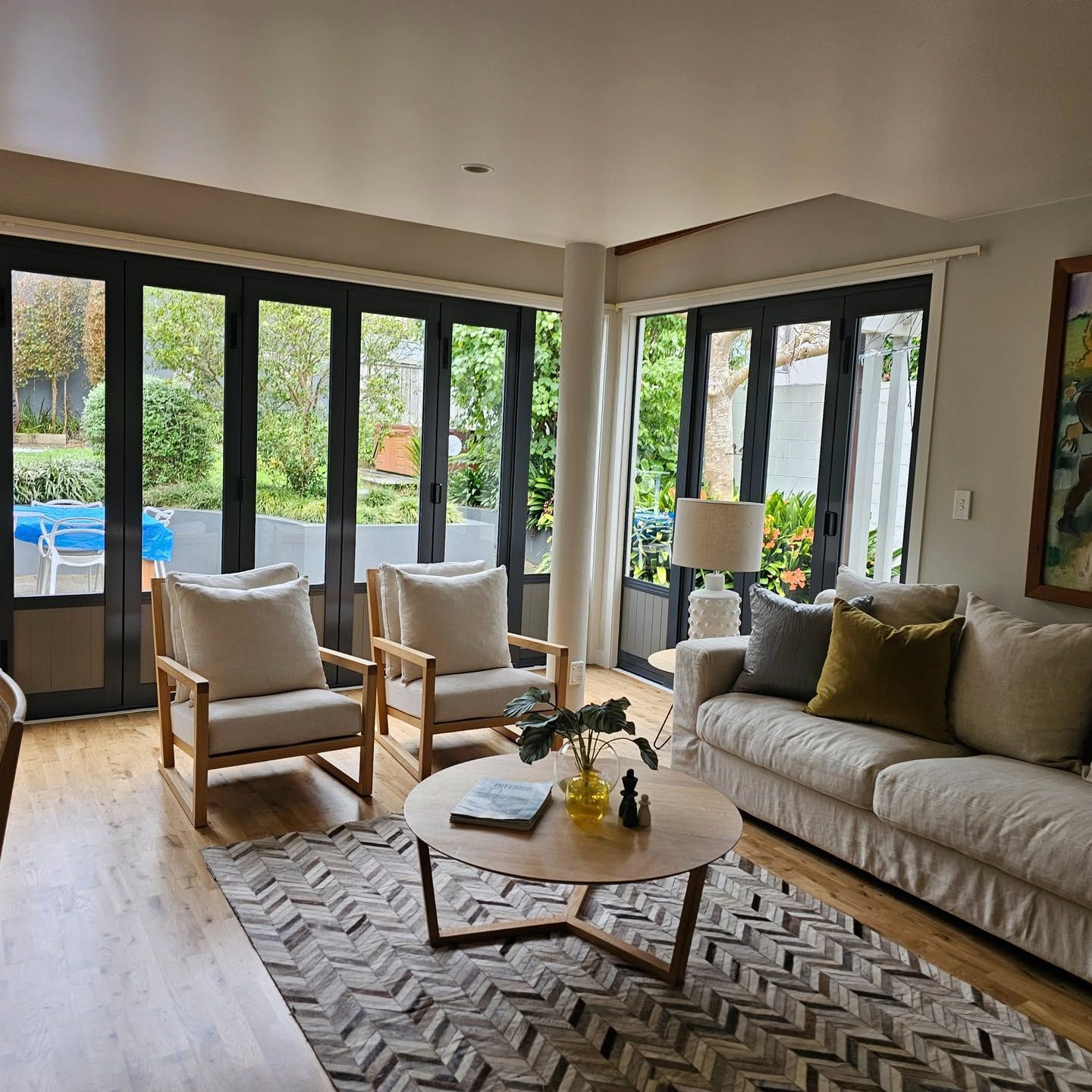 Living room with black-framed bifold doors opening to a pool
