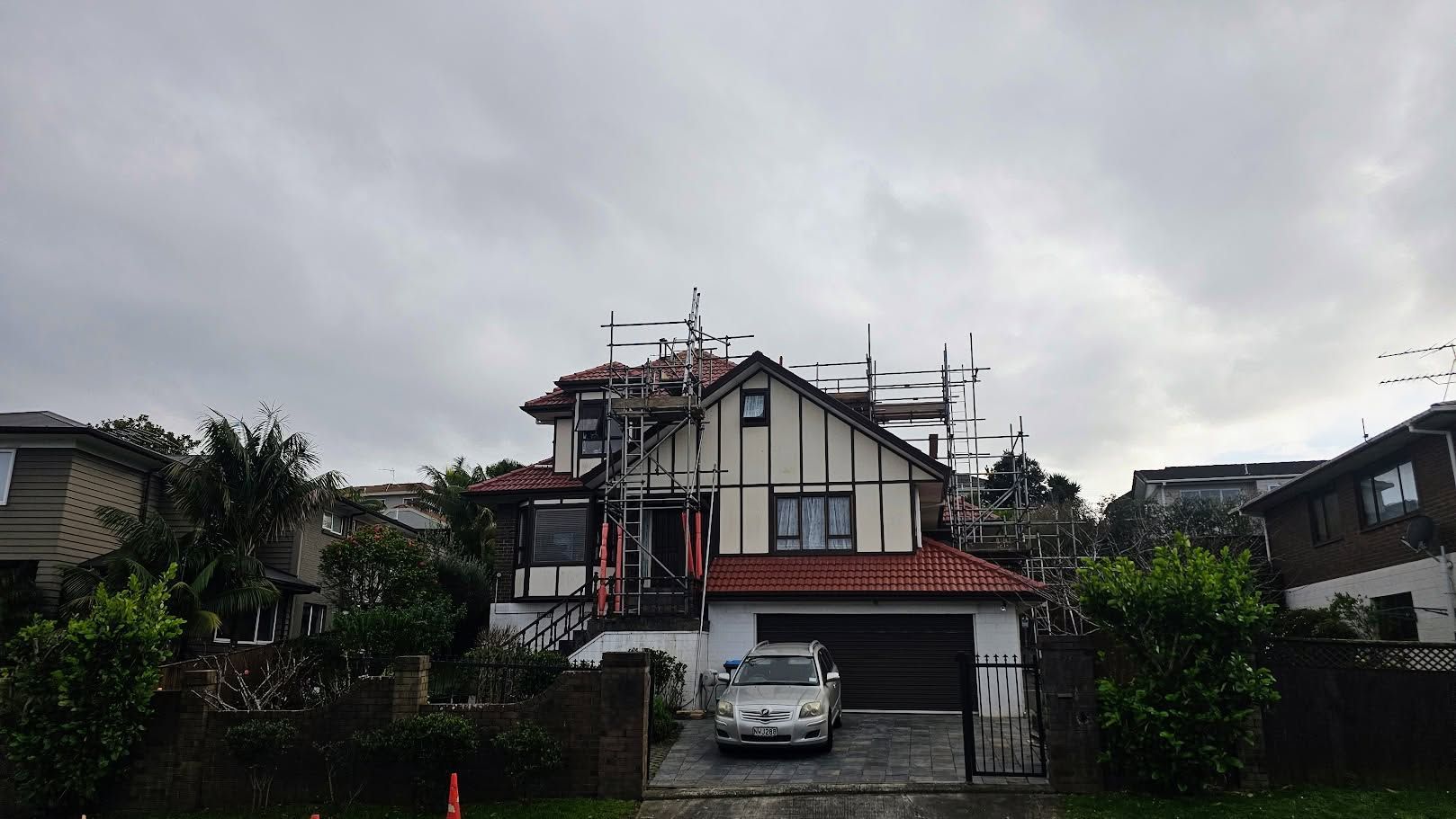 Two-story house exterior with dark trim and scaffolding under a cloudy sky