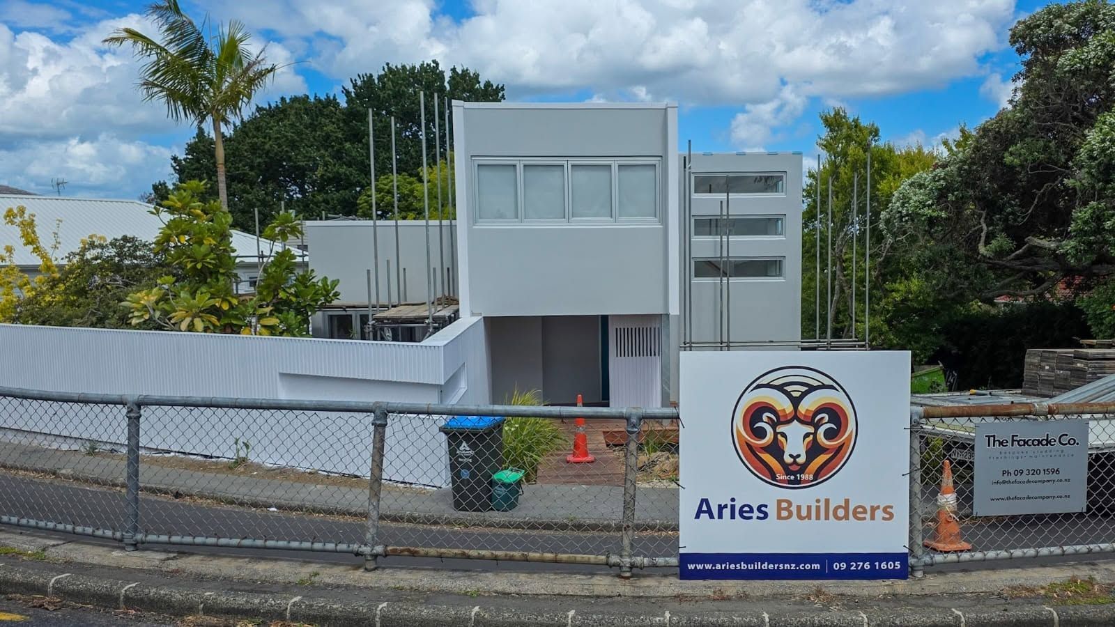 Modern building under construction with site sign on fence
