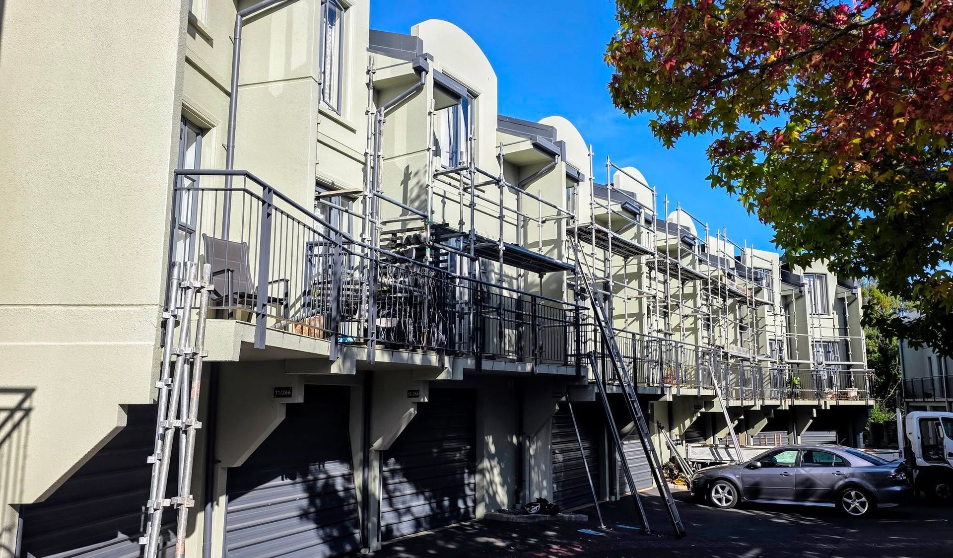 Row of townhouses with balconies and an autumn tree