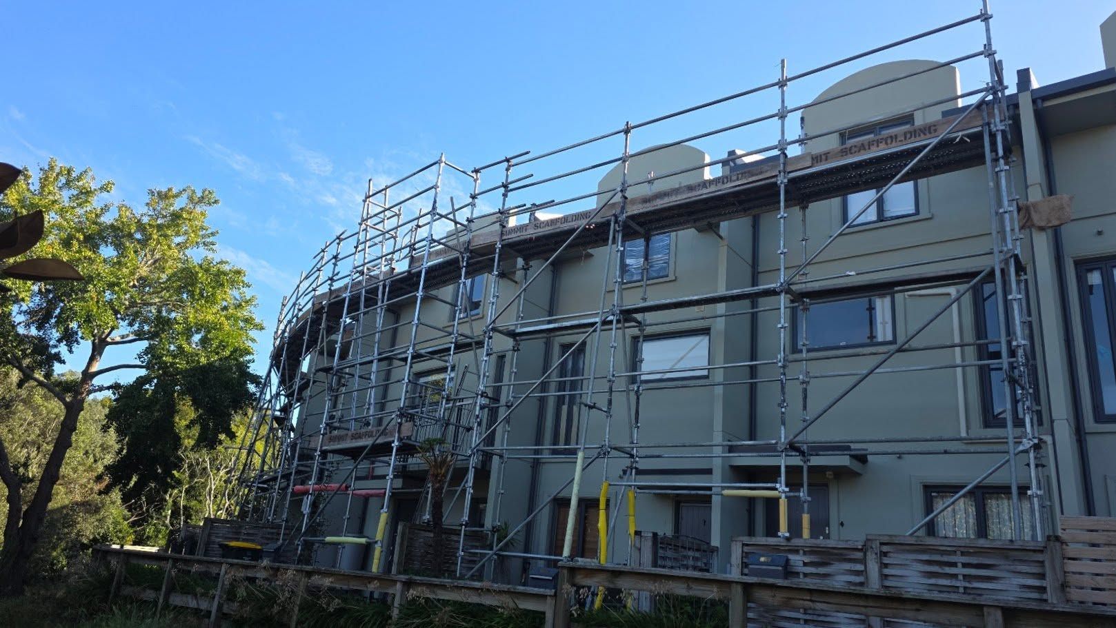 Apartment building covered in scaffolding under a blue sky