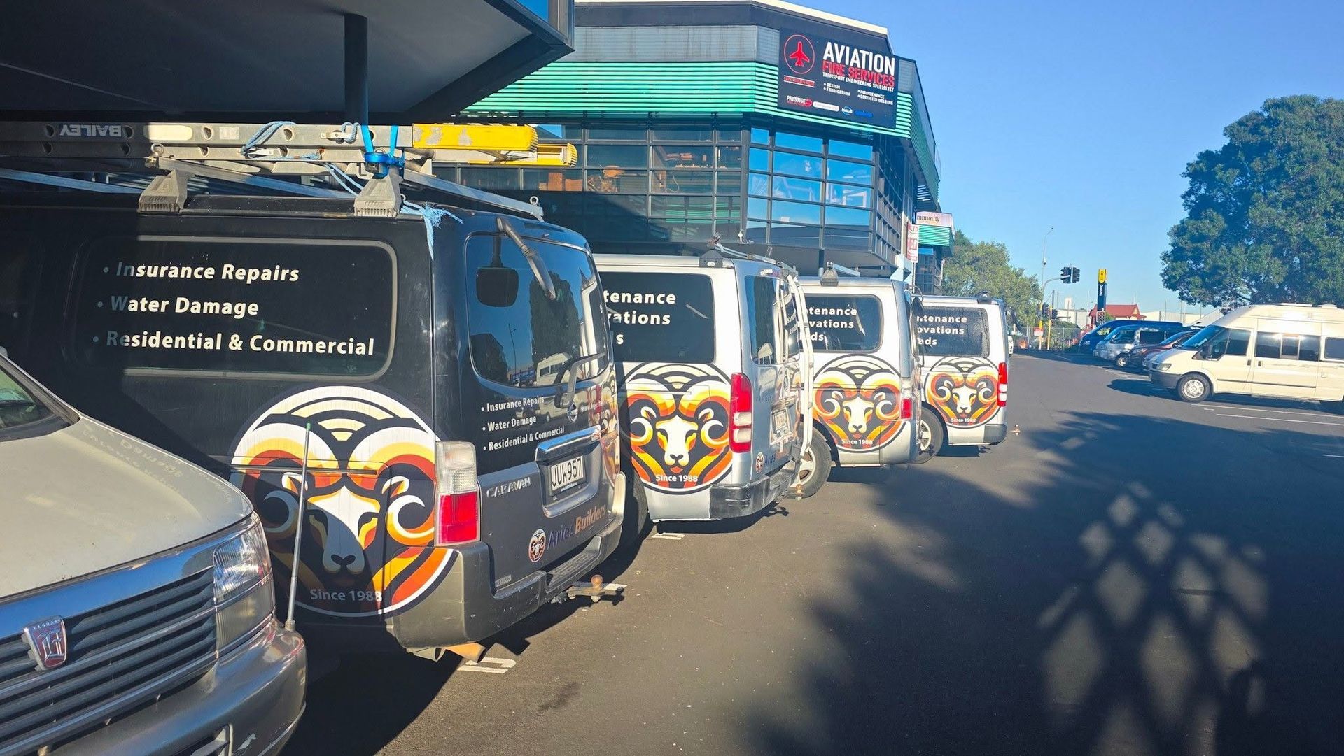 Line of branded restoration company trucks parked outside a building