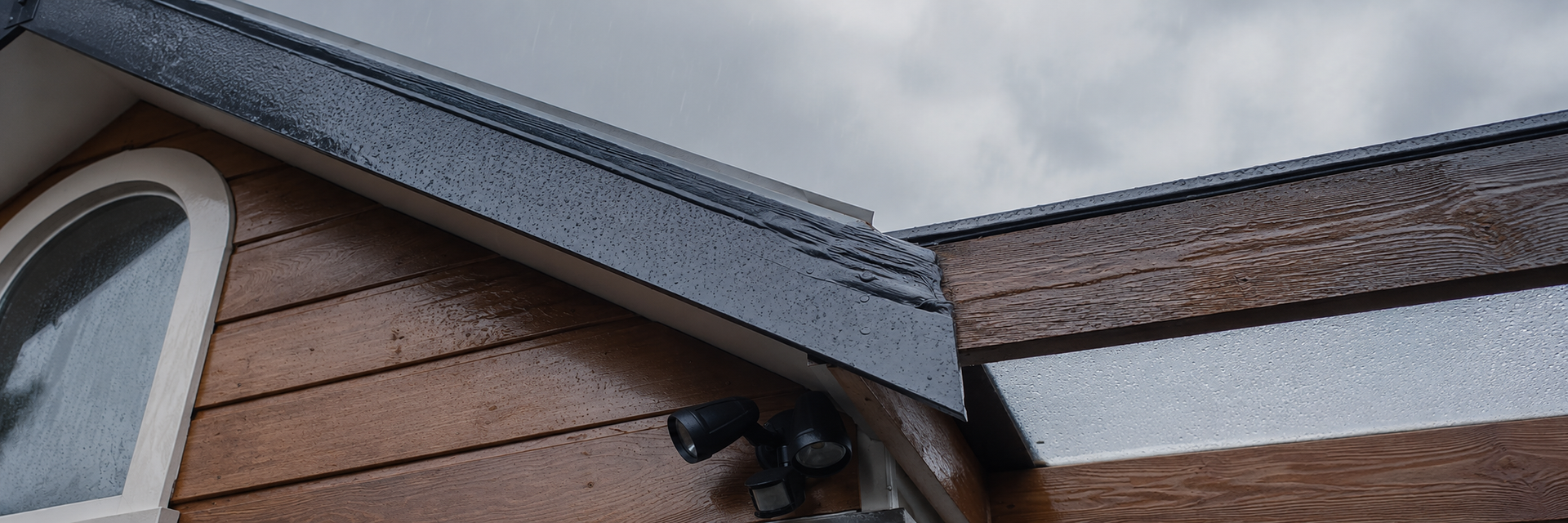Rain running off the roof edge, fascia and weatherboard cladding of an Auckland home during winter.