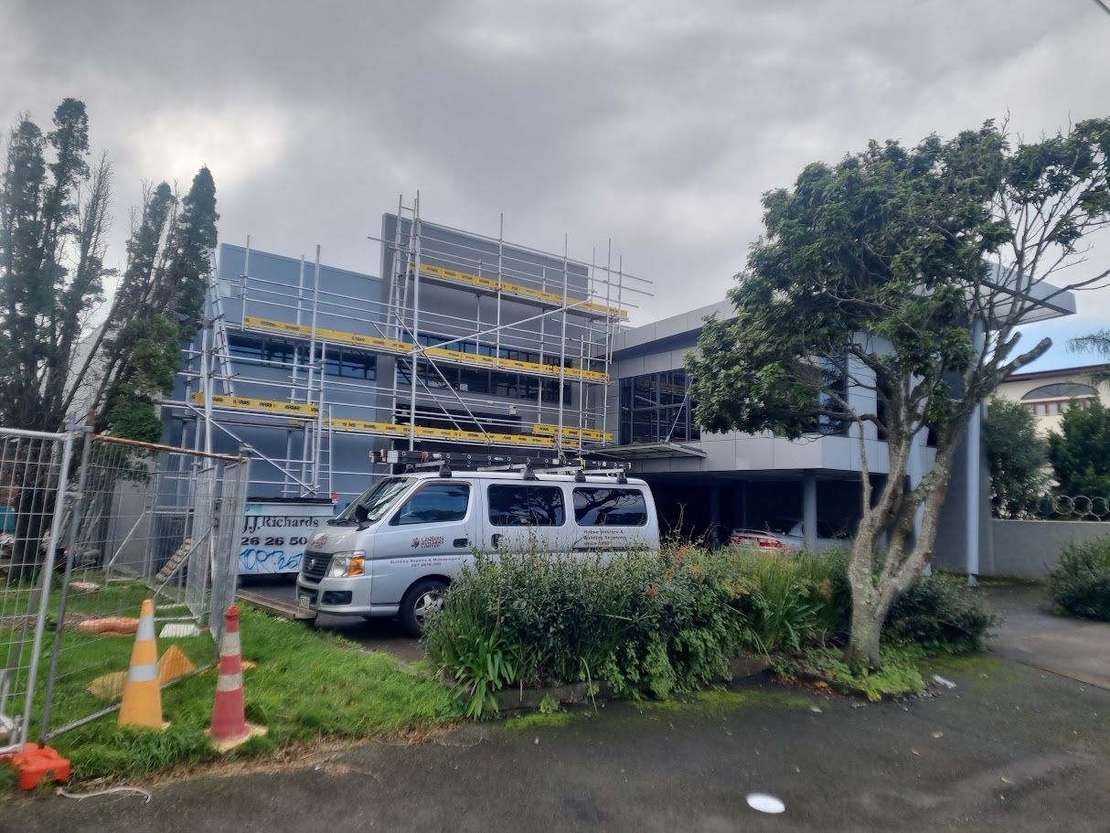 Building exterior covered in scaffolding among trees