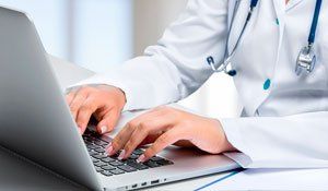 Um médico está digitando em um laptop.