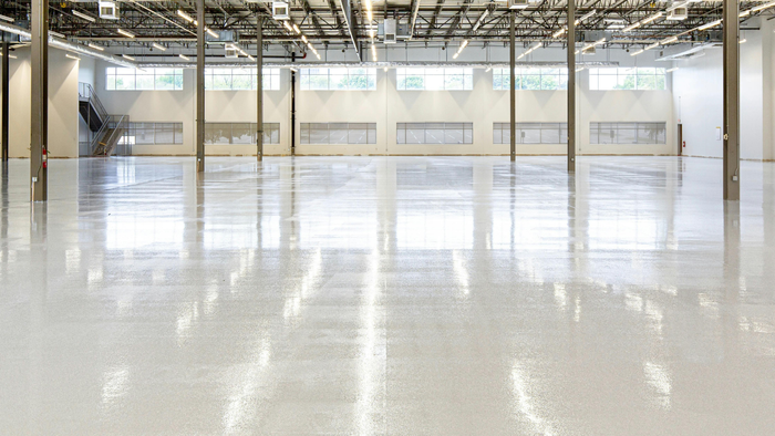 Empty industrial warehouse with a polished concrete floor and exposed ceiling beams
