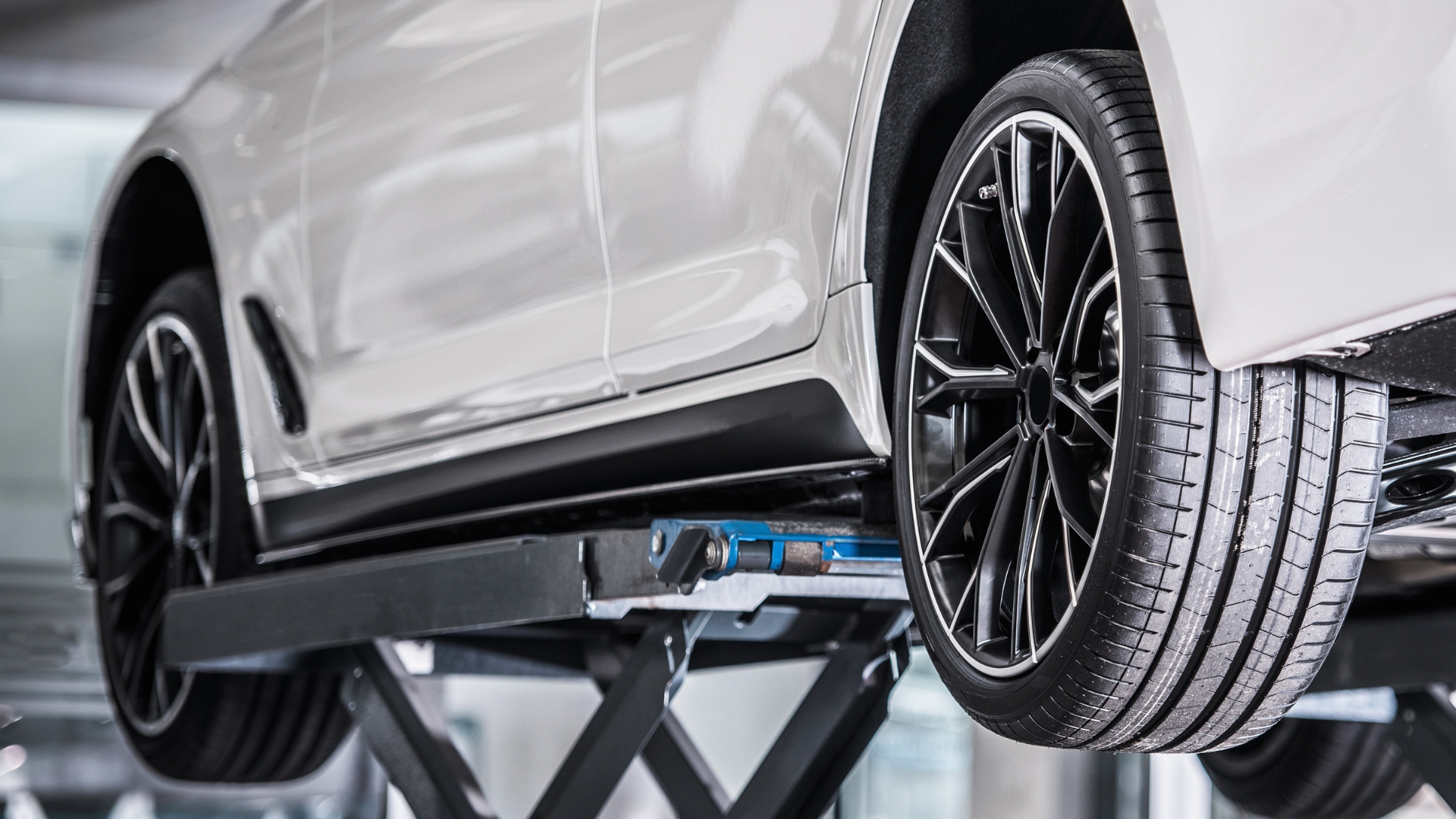 Silver SUV lifted on a car jack in a garage, rear wheel visible during maintenance