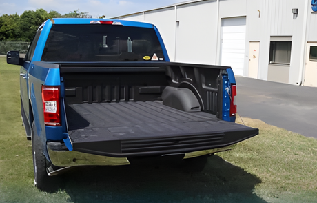 Blue pickup truck with tailgate down, showing the empty bed outside a building