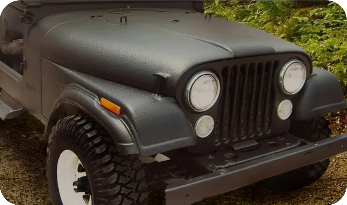 Matte black Jeep with round headlights and off-road tires parked outdoors