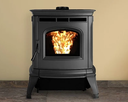 Harman Absolute Black wood-burning stove with a bright fire burning inside, against a beige wall on a tiled floor