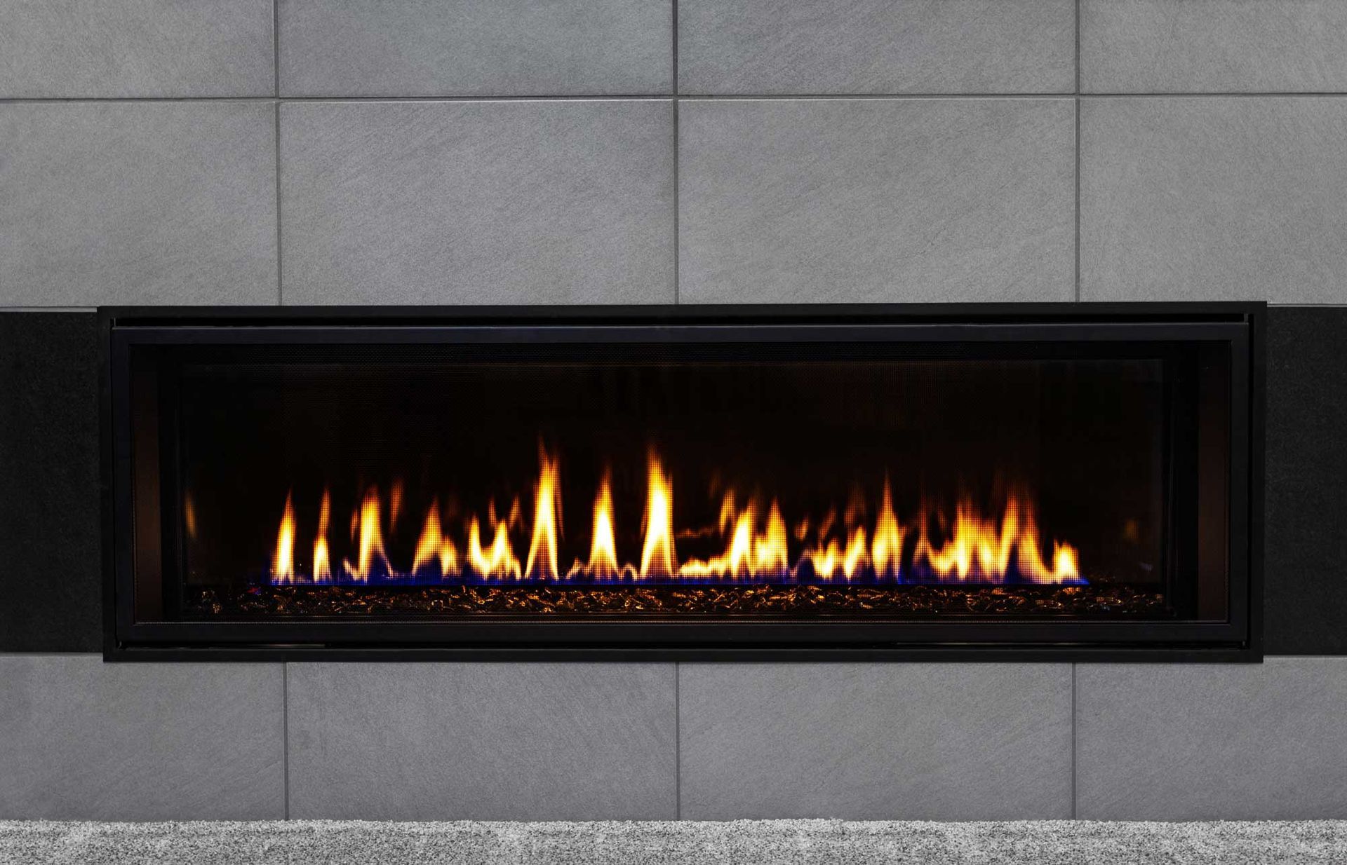 Modern gas fireplace. Modern black wall-mounted fireplace with a line of flames against a gray tiled wall