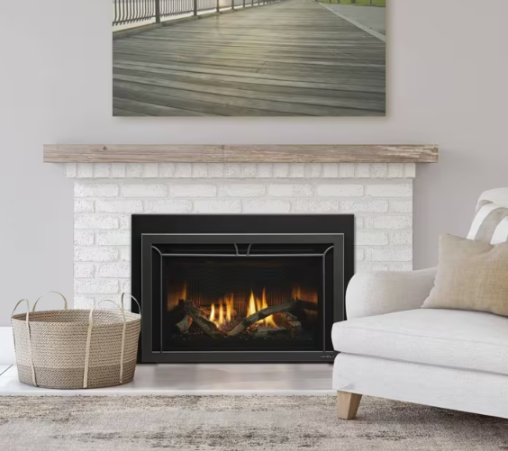 Heat & Glo Cosmo Cozy living room with white brick fireplace, lit fire, beige sofa, woven basket, and wall art