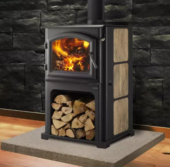 Quadra-Fire Discovery Series Black wood-burning stove with flames and stacked logs on a hearth against a dark stone wall