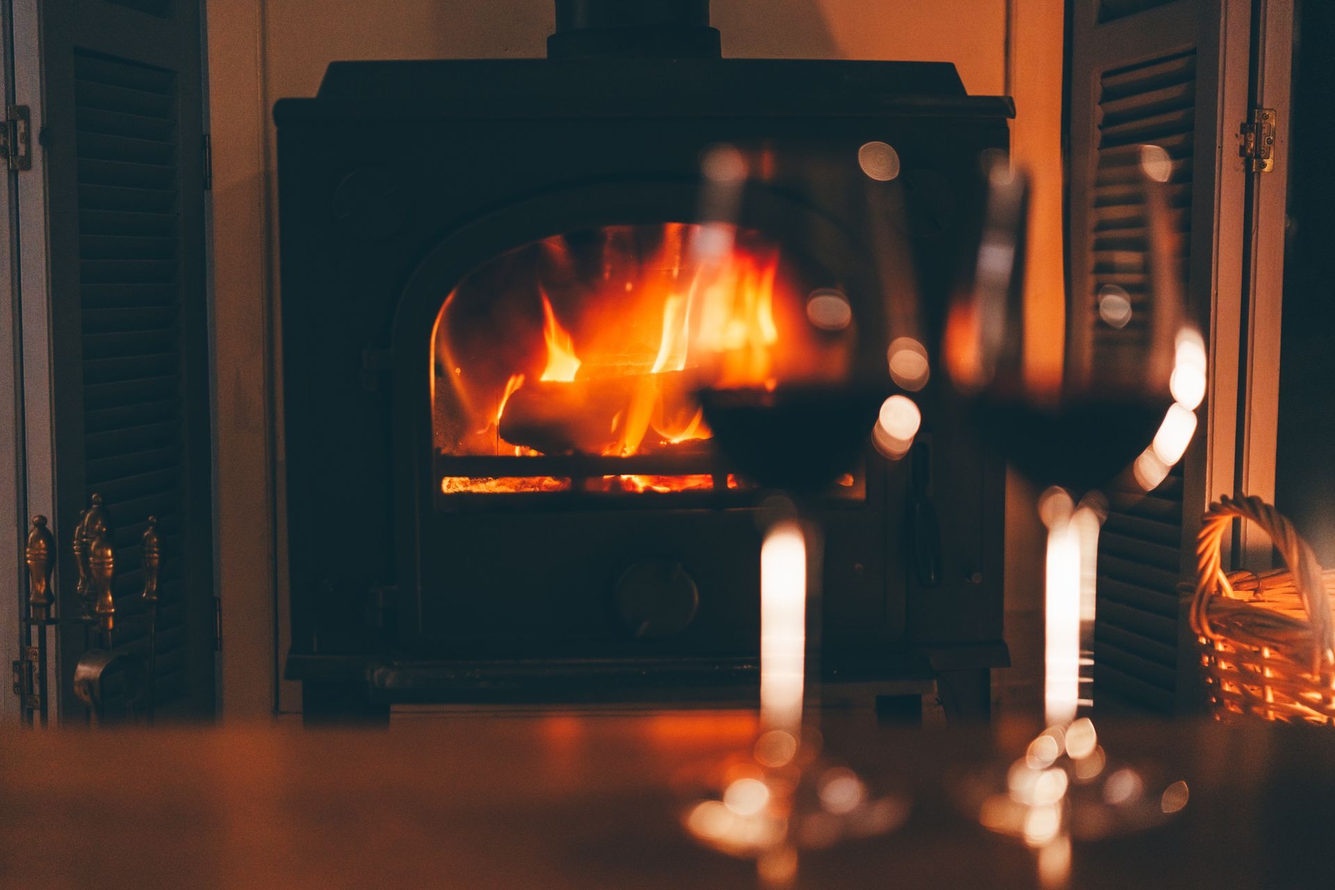 Cozy living room with a lit fireplace and blurred wine glasses in the foreground