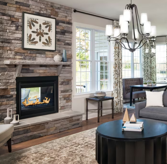 Living room with fireplace, two armchairs, and a coffee table. Modern living room with stone fireplace, chandelier, large windows, and gray sofa