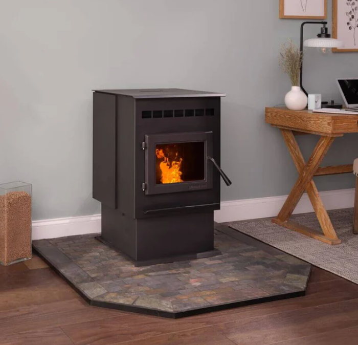 Quadra-Fire Outfitter Black pellet stove on a stone hearth in a cozy room with wooden flooring and a desk nearby