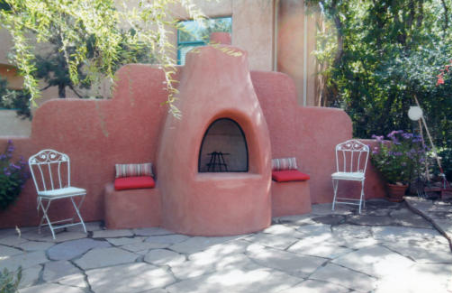 An outdoor fireplace has a pair of chairs in a lounge area. An outdoor fireplace has a pair of chairs in a lounge area.