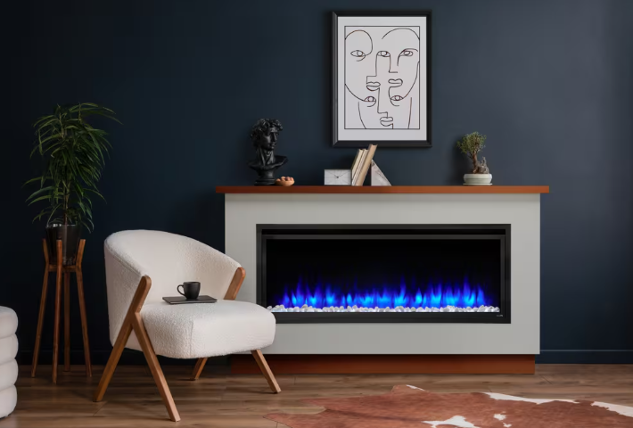 Living room with dining table, fireplace, window with light gray curtains. Modern living room with a white armchair, blue fireplace, dark wall, and framed abstract art
