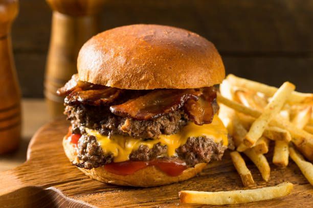 Grilled hatch green chile smashburger with bacon and fries on a wooden table