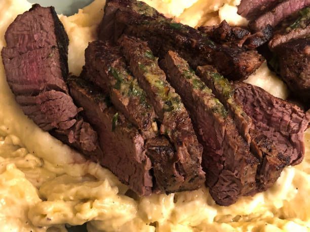 Sliced grilled Arizona ugly steak served over mashed potatoes on a plate
