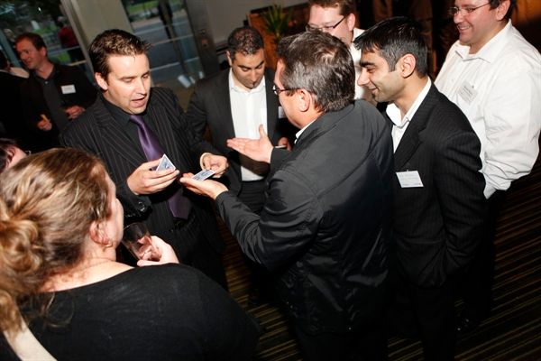 People at an event, one man performs a card trick.