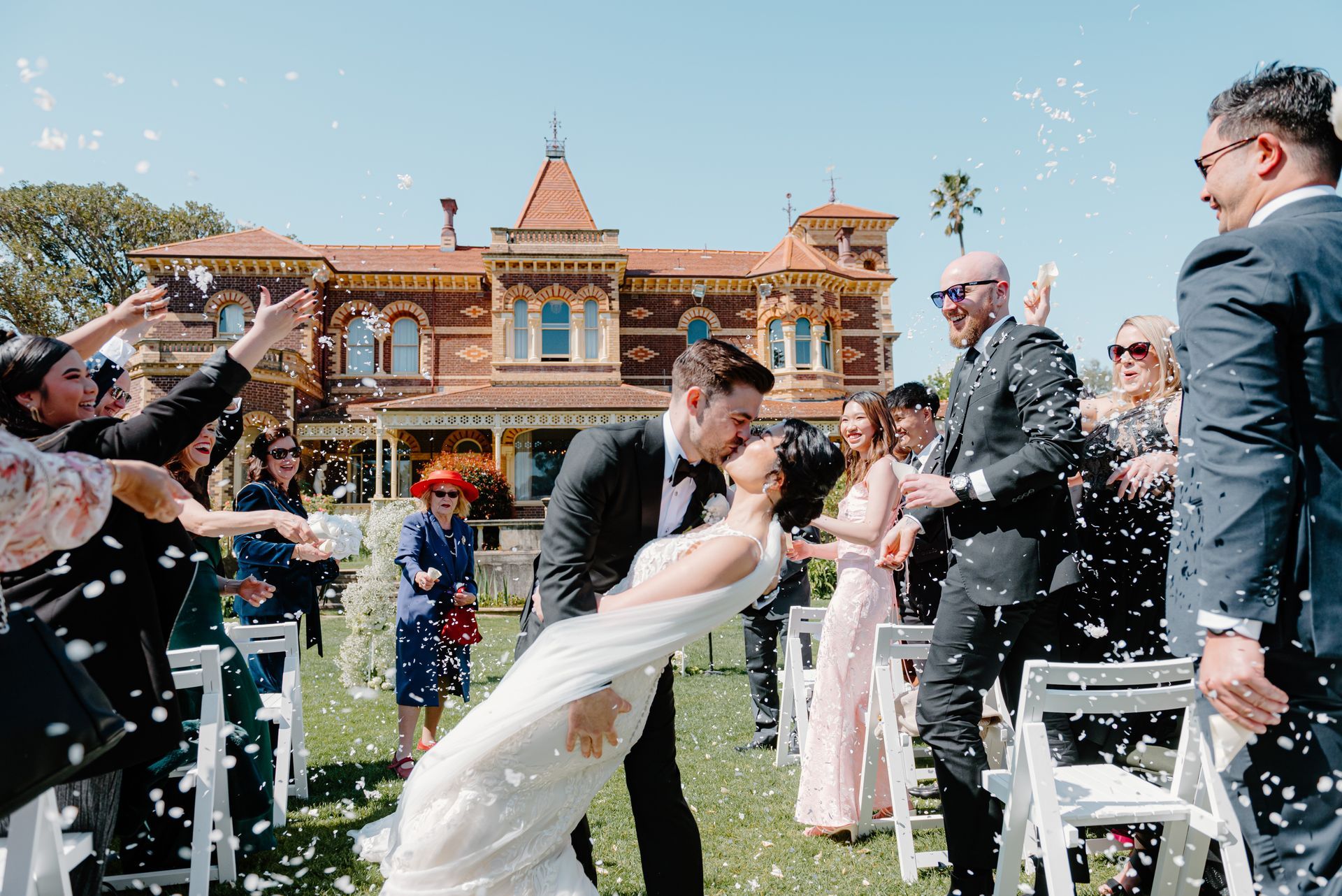 A bride and groom are kissing in front of a crowd of people.