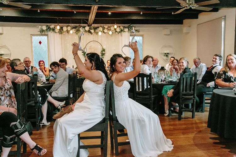 Two women in wedding dresses are sitting next to each other in a room.