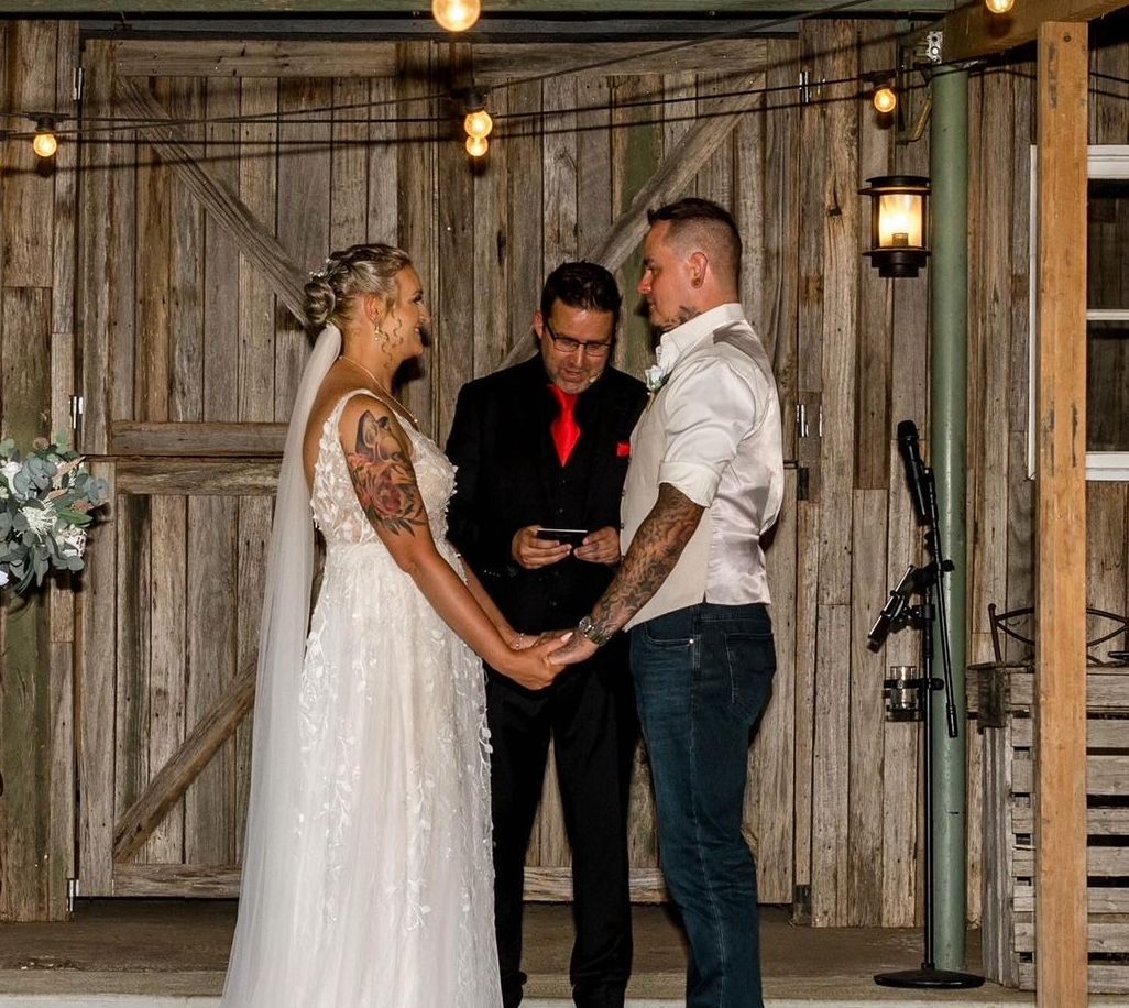 A bride and groom are holding hands during their wedding ceremony.