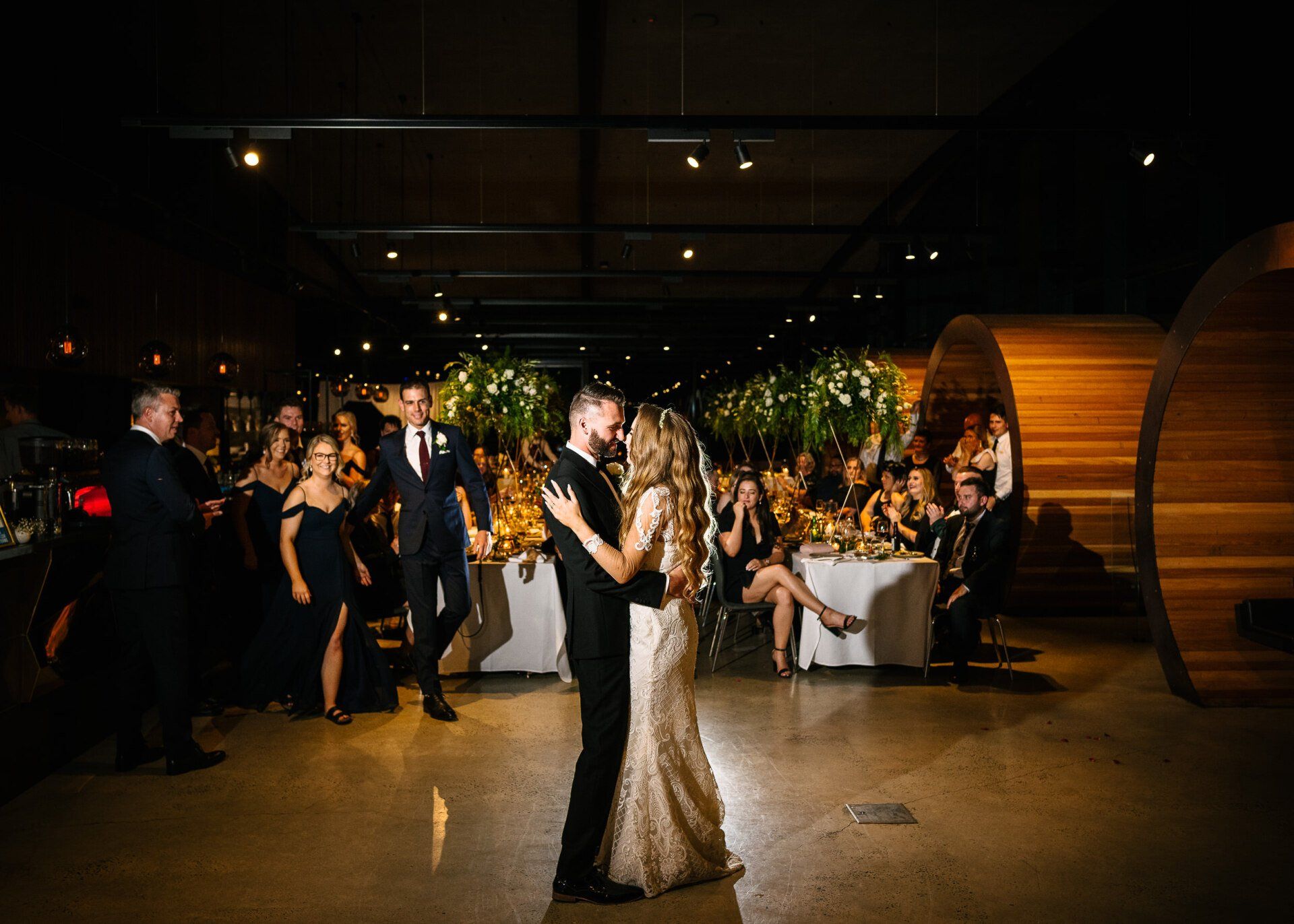 A bride and groom are dancing at their wedding reception in front of their wedding guests.