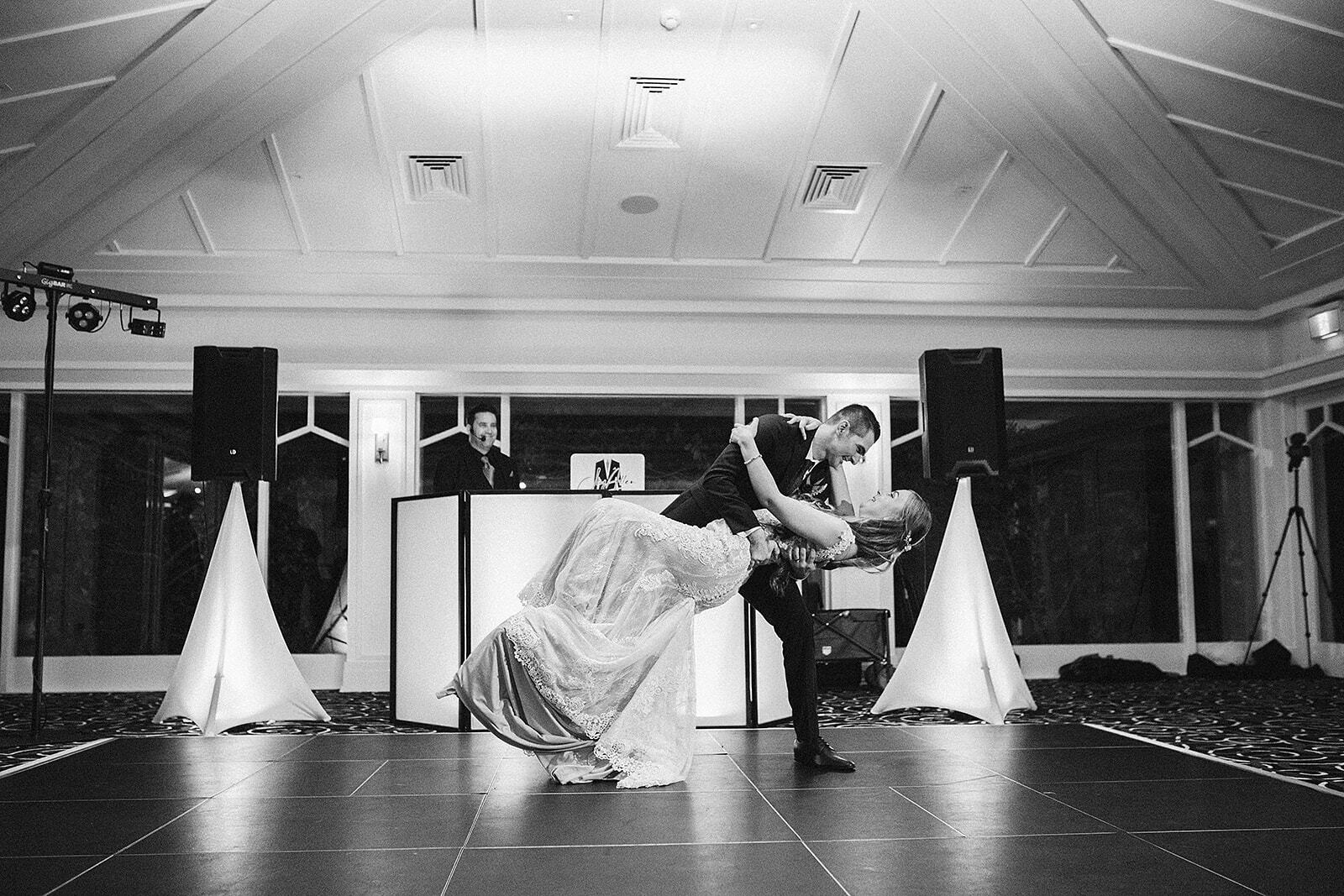 A black and white photo of a bride and groom dancing on a dance floor.
