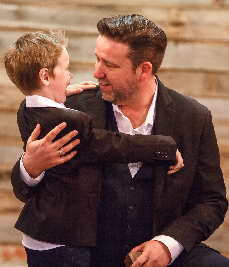 A man in a suit is holding a little boy in his arms
