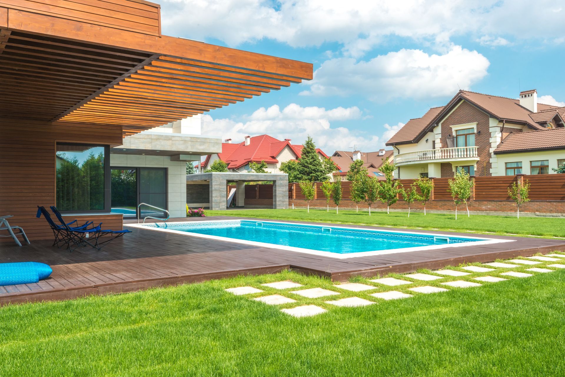 Modern backyard with a swimming pool, patio seating, green lawn