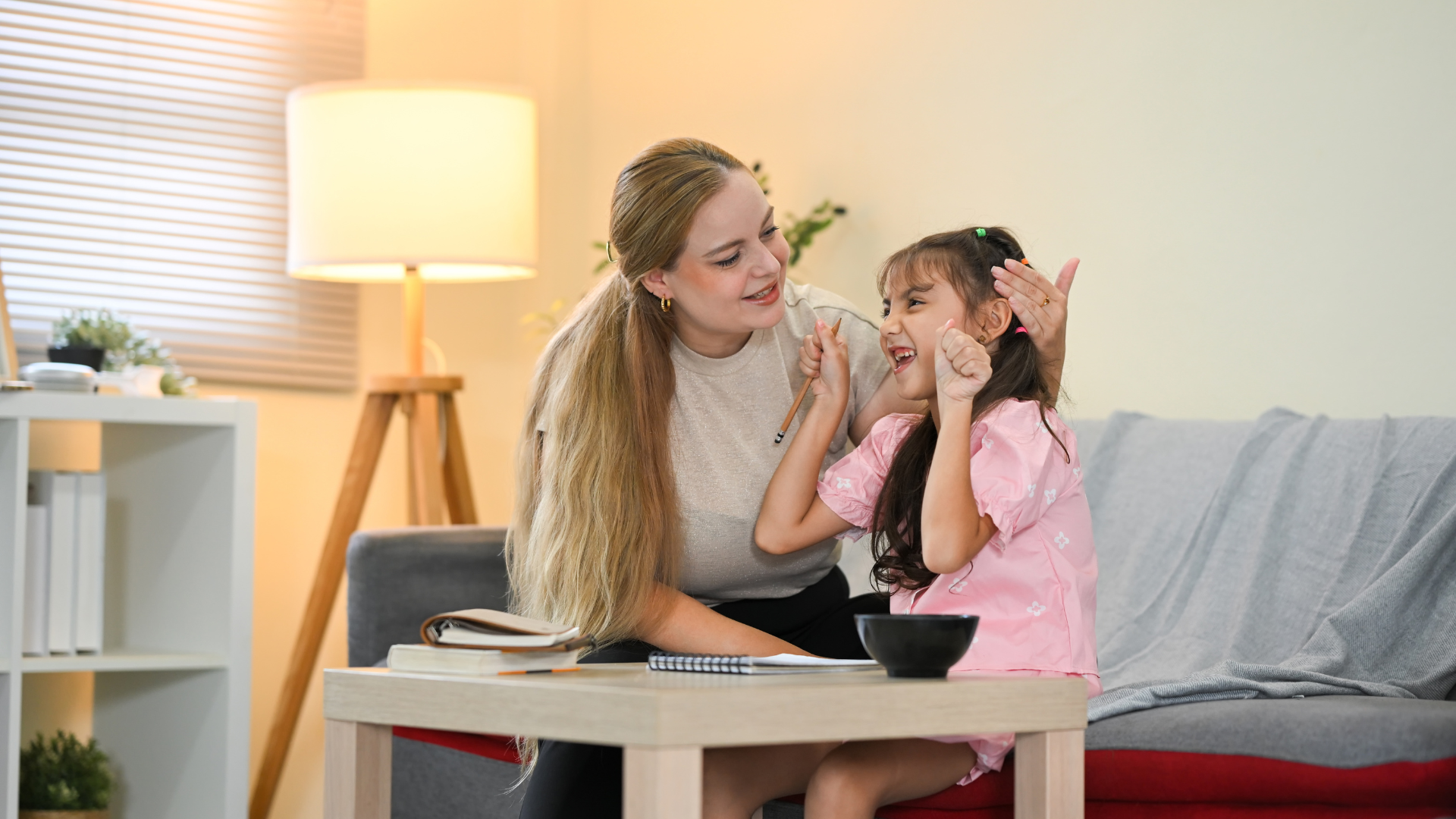 Woman smiles at child, touching her face; living room setting.