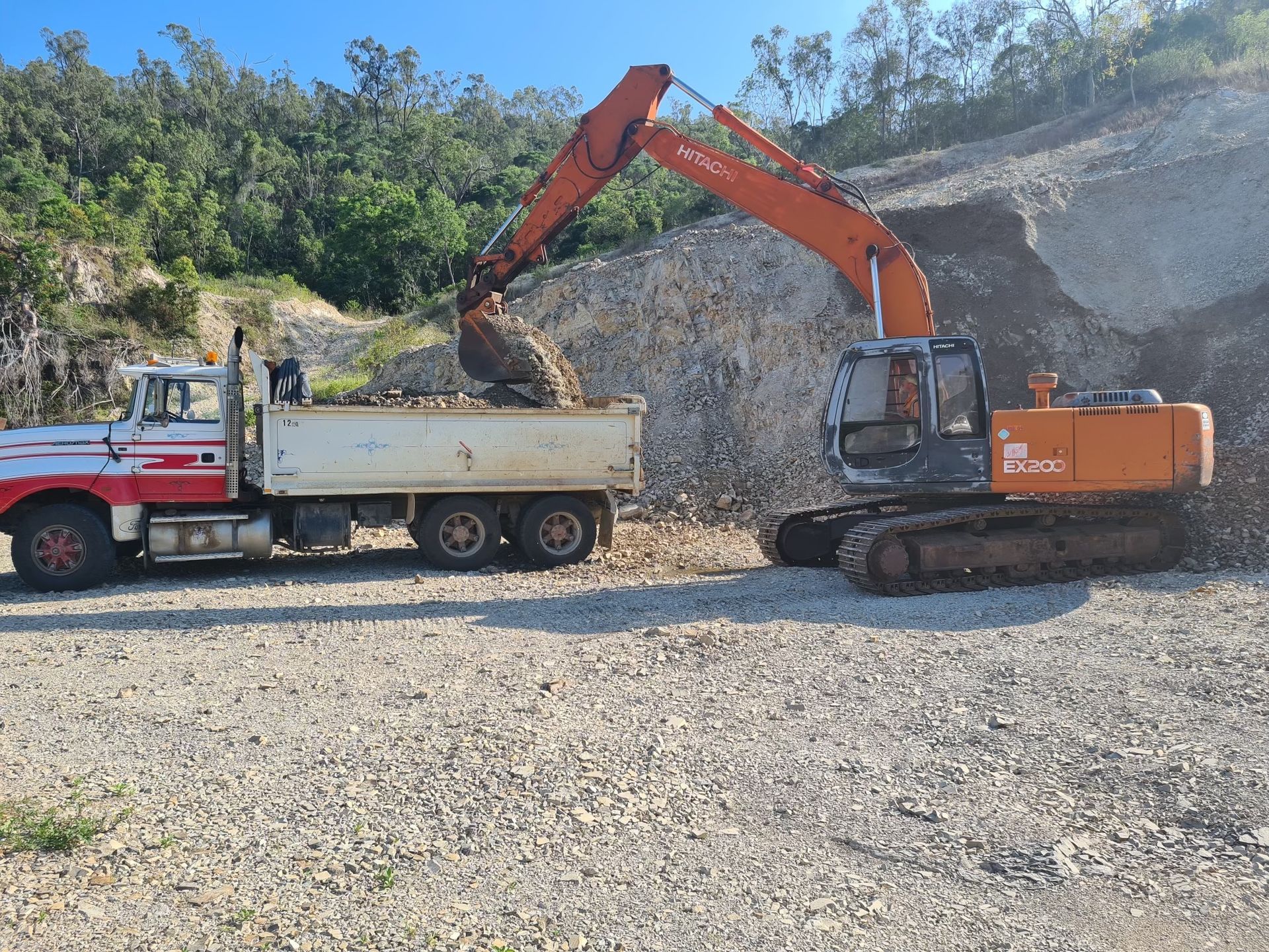 A Red And Orange Road Roller Is Driving On A Dirt Road Next To A Pile Of Dirt — Blue Dog Hire Qld In Mackay, QLD