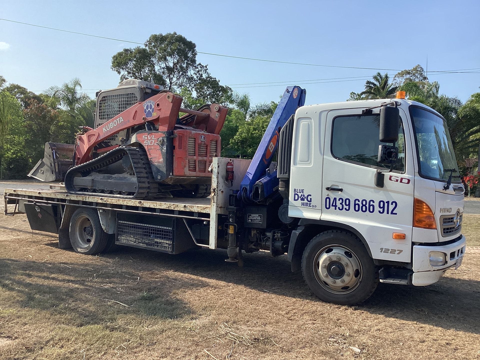 A Tilt Tray Truck In The Dirt With A Bobcat on the Back — Blue Dog Hire Qld In Midge Point, QLD