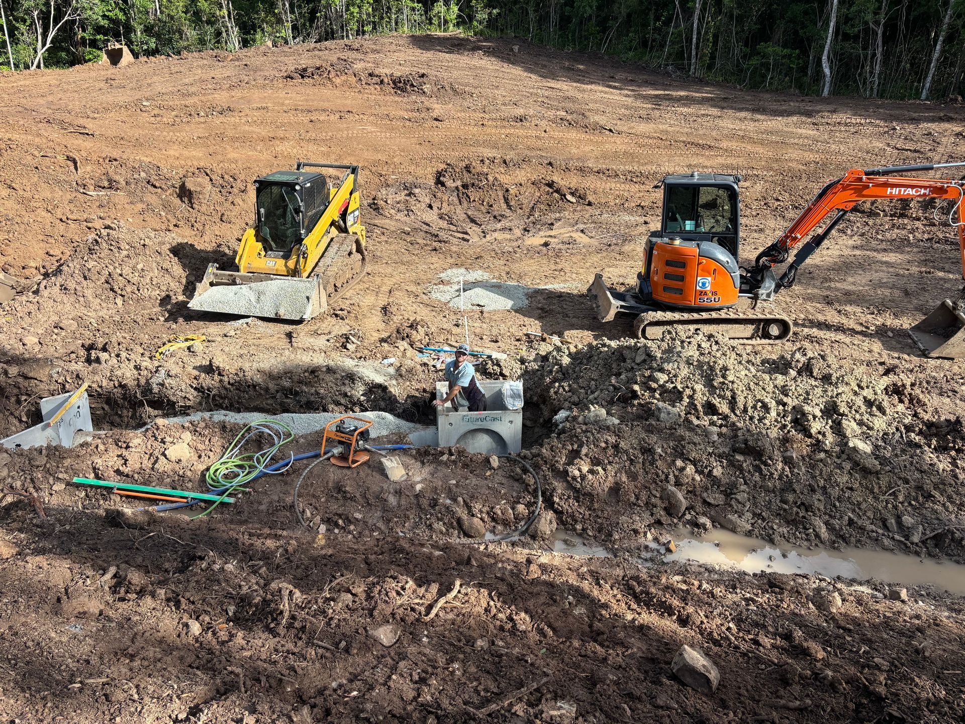 Two Compact Excavators Working On A Muddy Construction Site — Blue Dog Hire Qld In Mackay, QLD