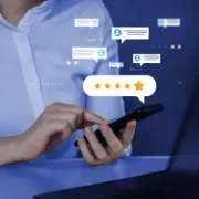 Person using a smartphone with glowing review ratings and chat icons on a blue background