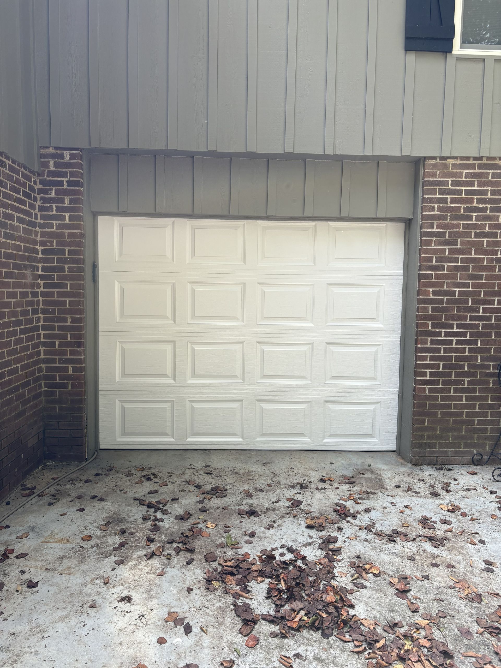 White garage with a truck parked in front; green grass, trees in the background.