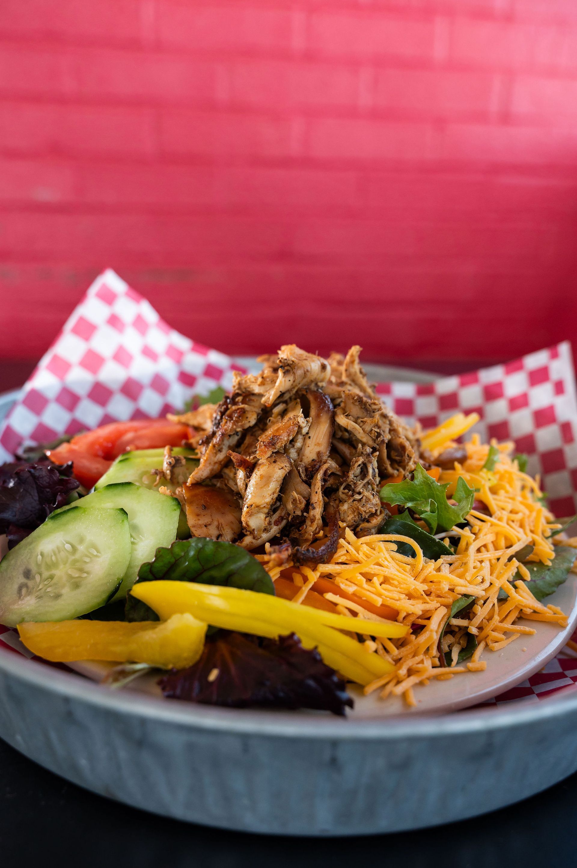 Close-up of a colorful salad bowl with shredded meat, cucumber, carrots, peppers.