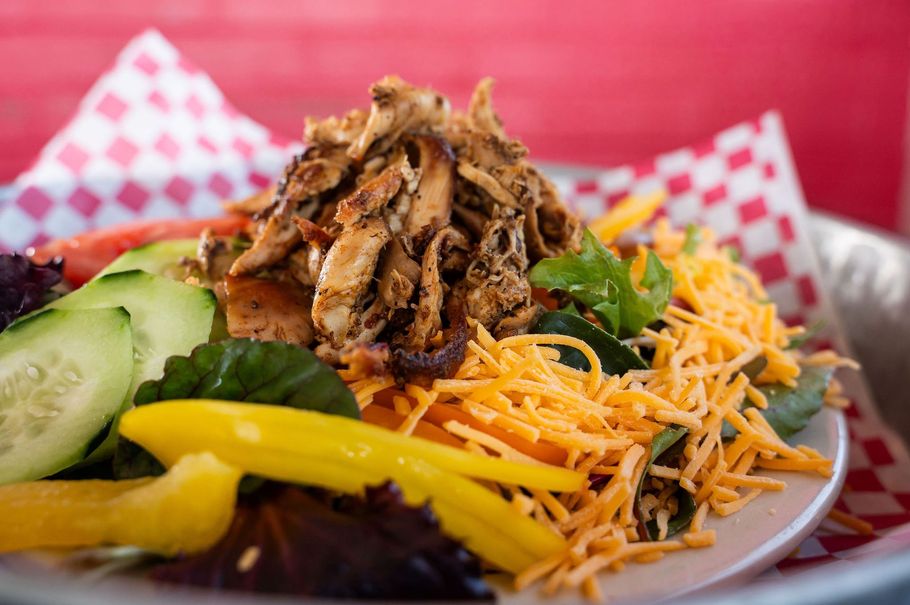 Shredded meat salad with shredded cheese, cucumbers, and yellow bell peppers on a plate