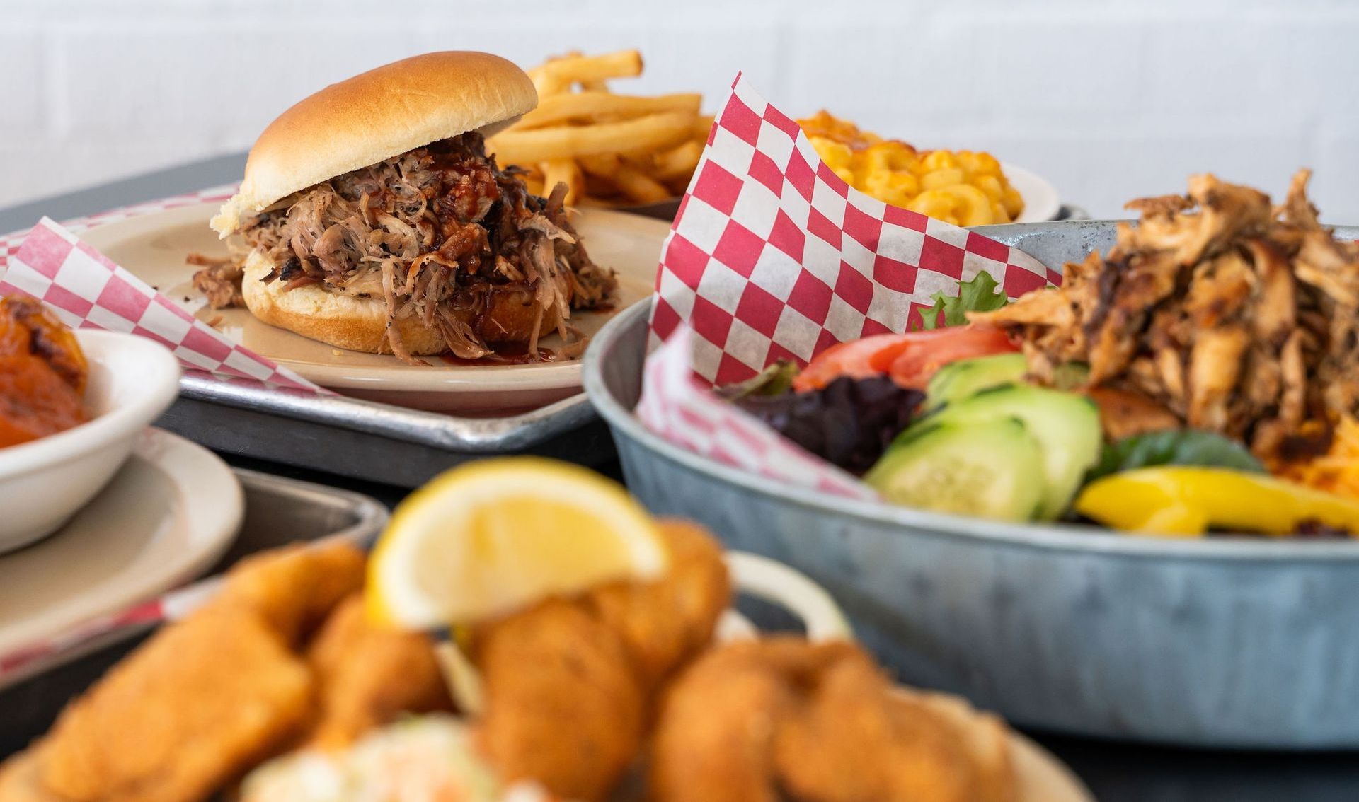 Table of burgers, fries, and fried chicken with avocado slices in checkered baskets