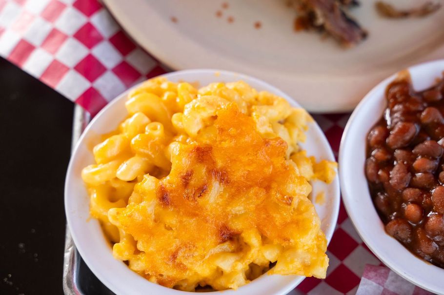 Bowl of cheesy scrambled eggs with baked beans on a red-and-white checkered tablecloth