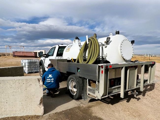A Man is Kneeling Next to a Vacuum Truck | Cheyenne, WY | Toilets On The Go, LLC